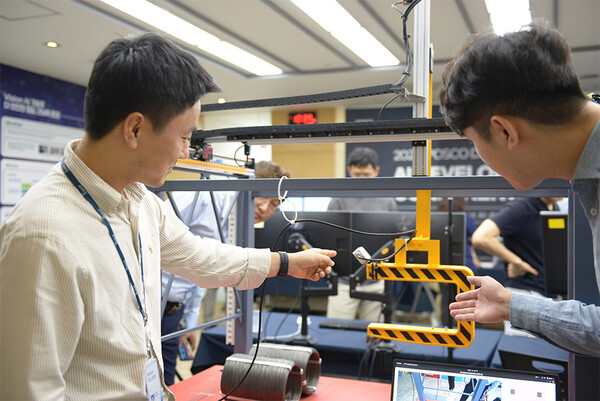 포스코DX AI기술센터 연구원들이 산업용 AI가 적용된 크레인 모의장치를 시연하고 있다.