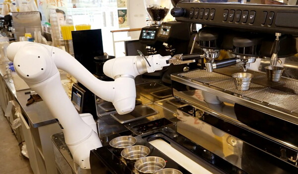 두산로보틱스 협동로봇이 원두가 담긴 포터필터를 커피머신에 장착하고 있다.