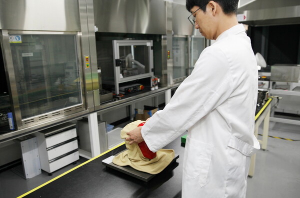 FITI시험연구원 연구원이 방화두건 시험평가를 진행하고 있다.