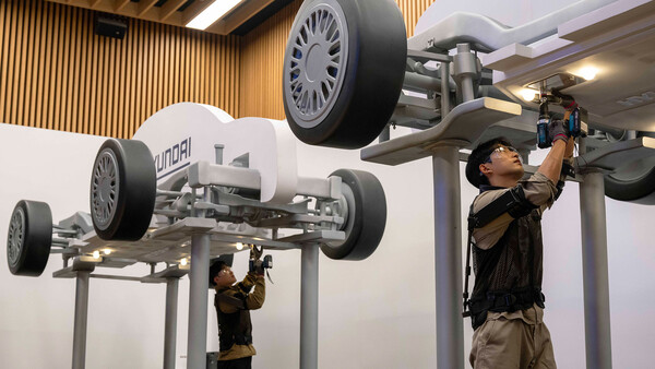 웨어러블 로봇 테크데이에서 상완 근력을 보조하는 '엑스블 숄더' 로봇을 착용한 로보틱스랩 연구원이 팔을 올려 모형 차량 하부의 부품을 체결하고 있다.