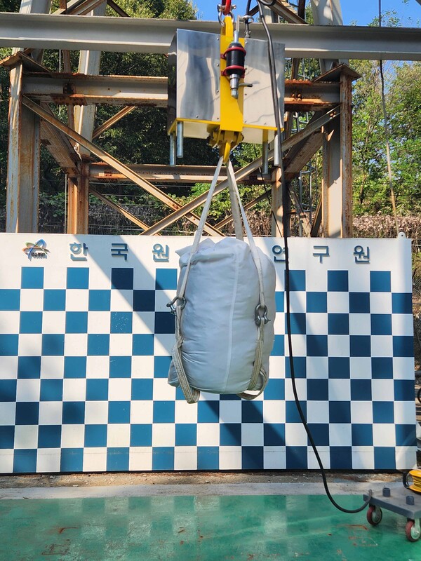 비분산 포장재에 입자성 물질 함유 폐기물 모사 시료를 넣은 후 낙하 시험을 수행하고 있다.